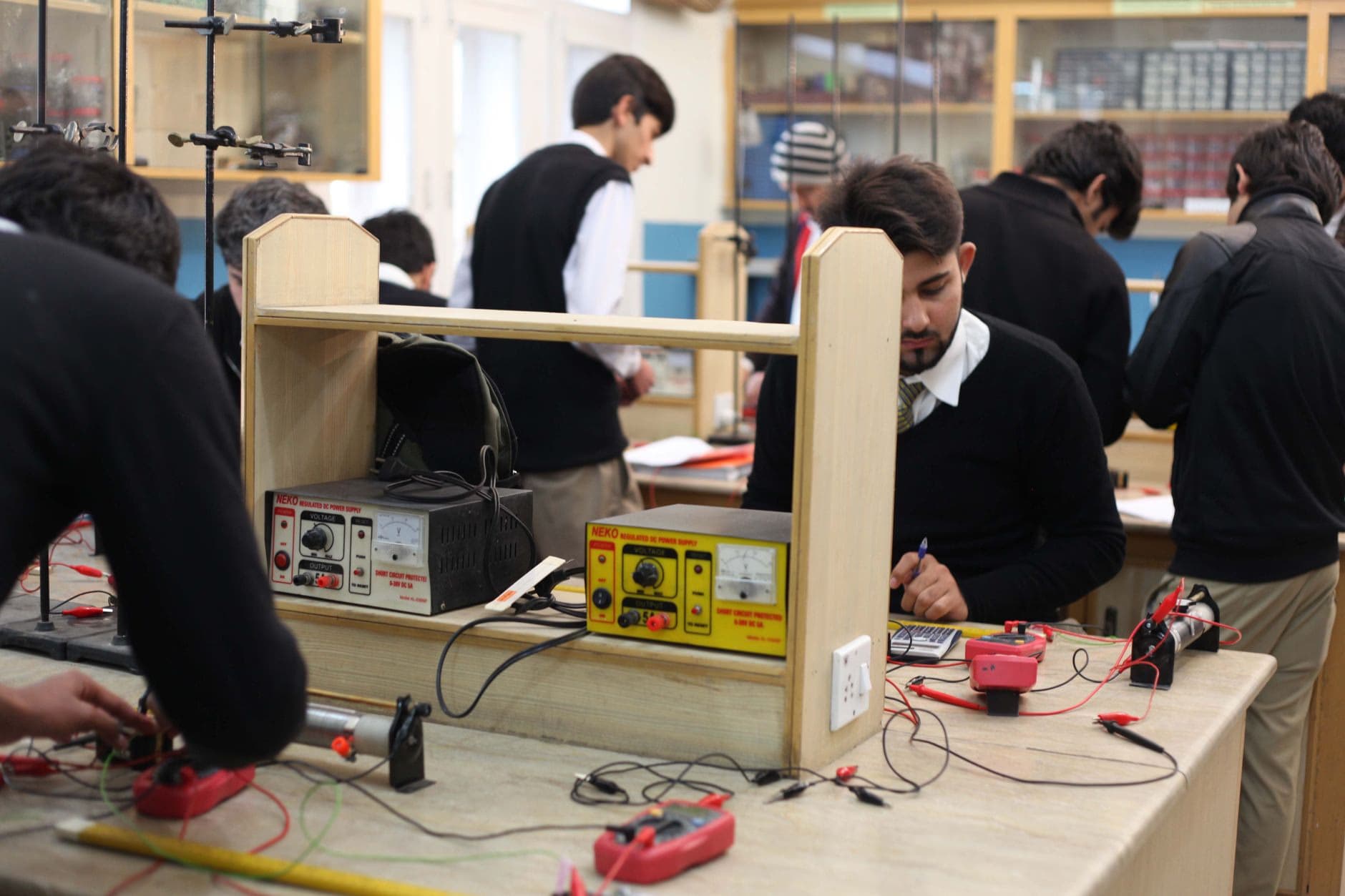 Students working with DC power supplies and circuits in a physics lab