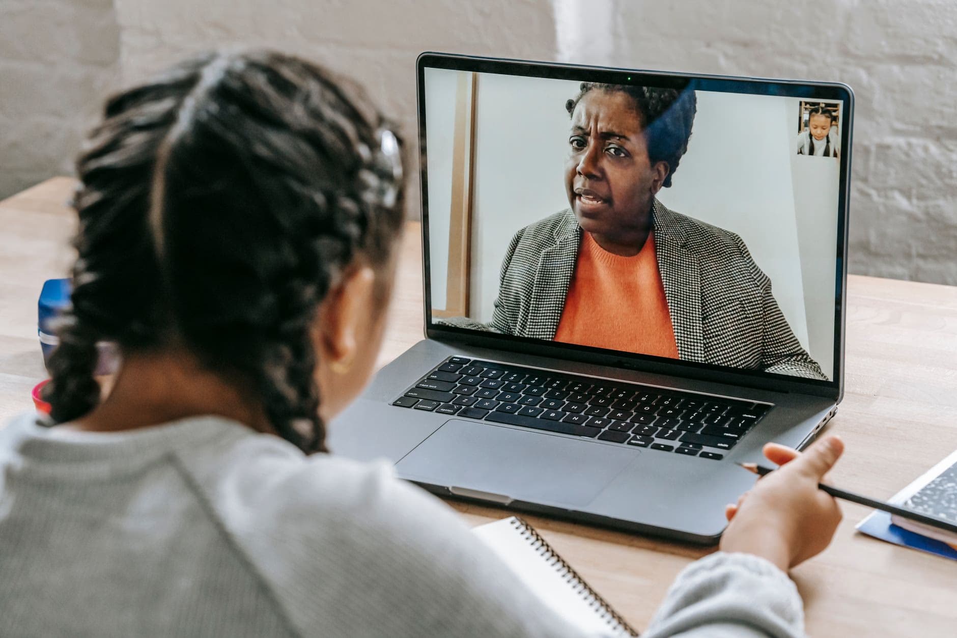 A student in an online video lesson with a tutor on a laptop