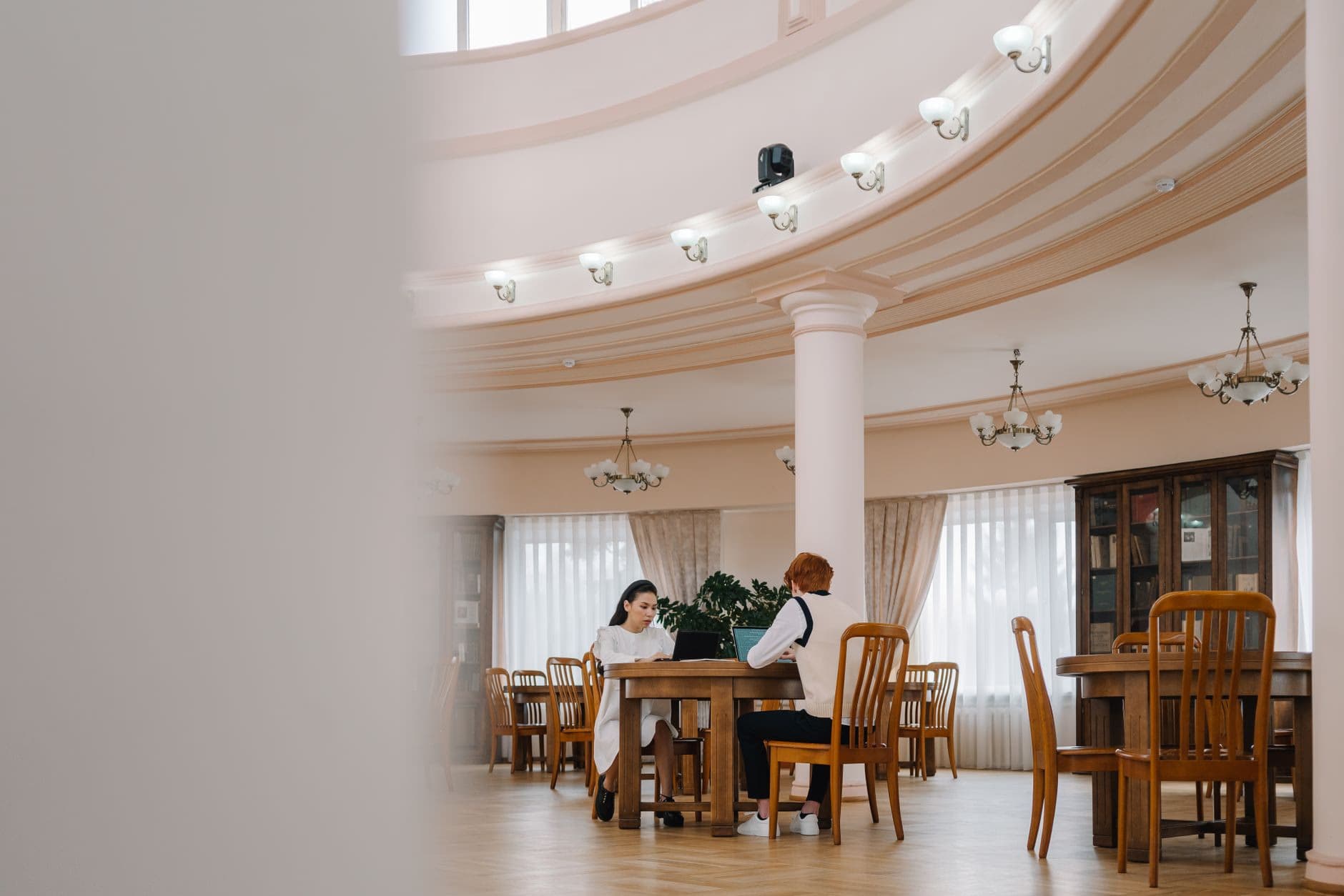 Two students working at tables inside a library