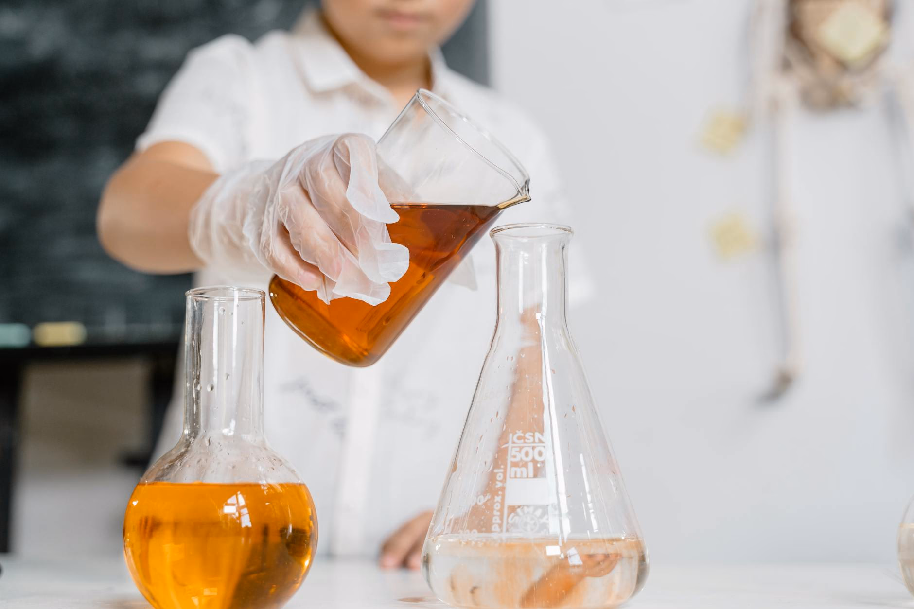 Student pouring liquid into a flask during a chemistry experiment