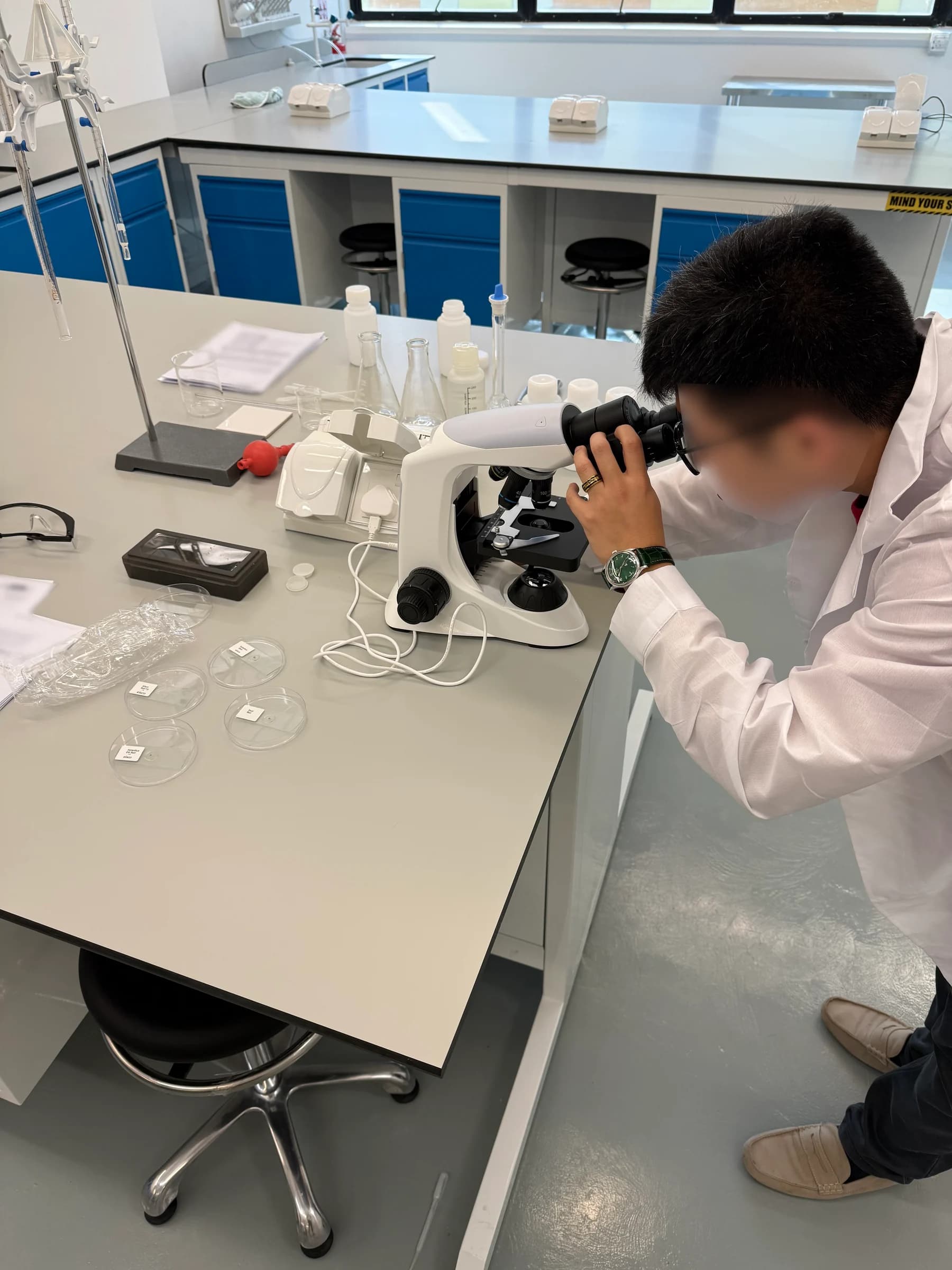A student looking through a microscope at a laboratory bench during an Eclat practical session