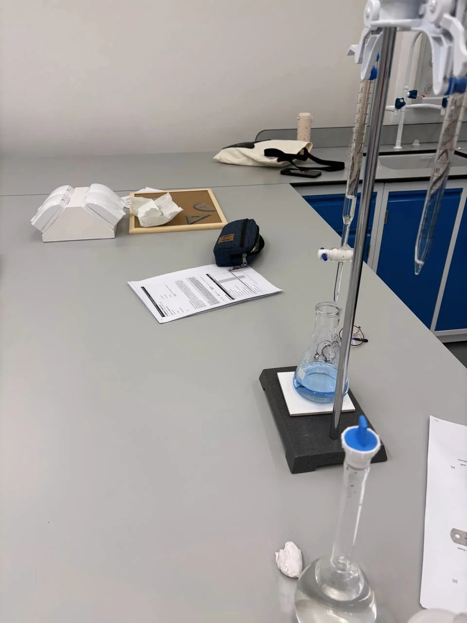 A burette held above a conical flask on an Eclat laboratory bench