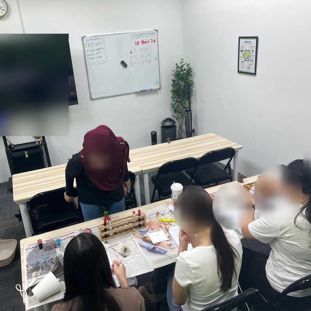 Tutor guiding students during an O-Level Biology practical session