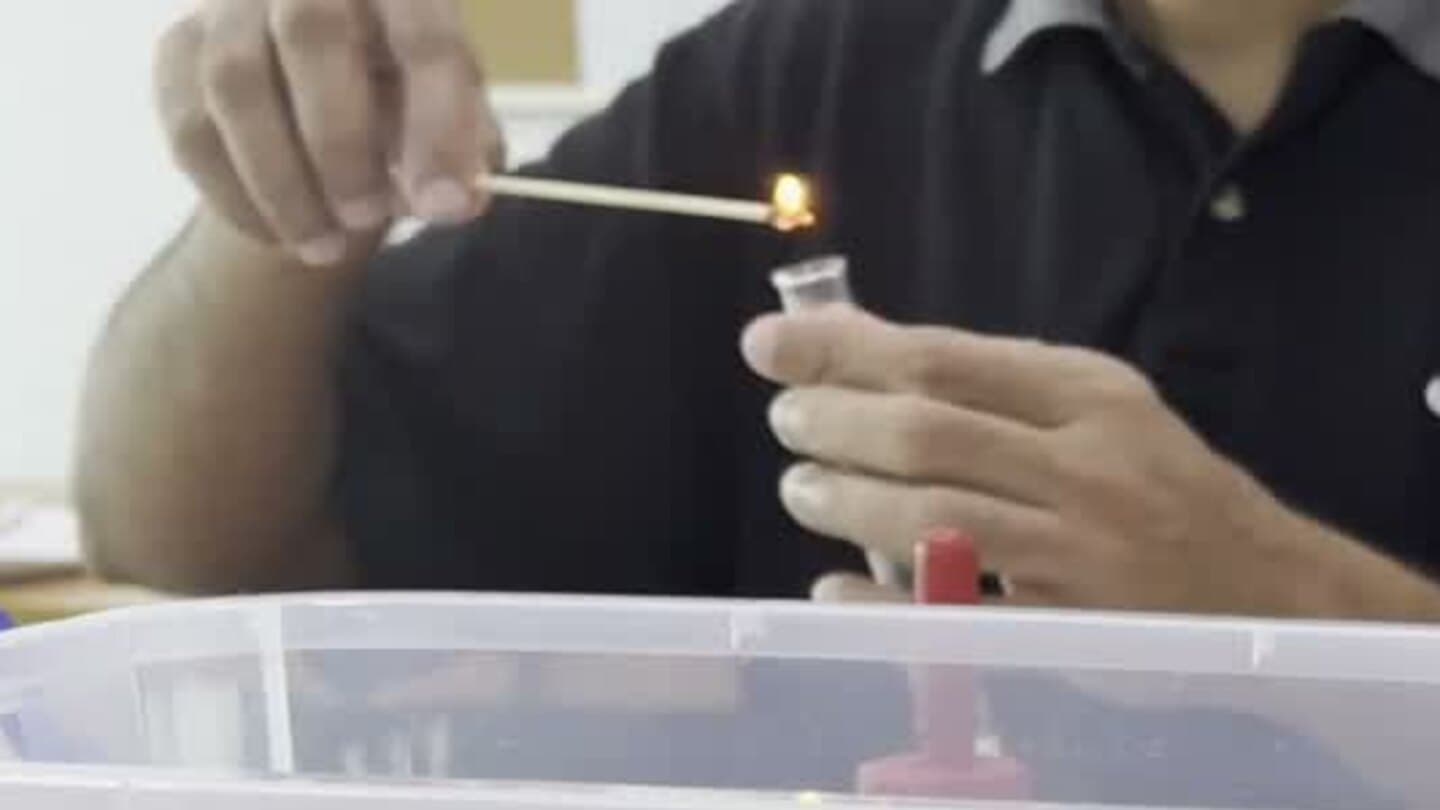 A student holding a burning splint above a test tube during an Eclat Chemistry gas test