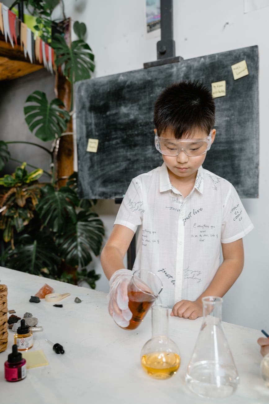 A student wearing safety goggles pouring liquid during a chemistry experiment