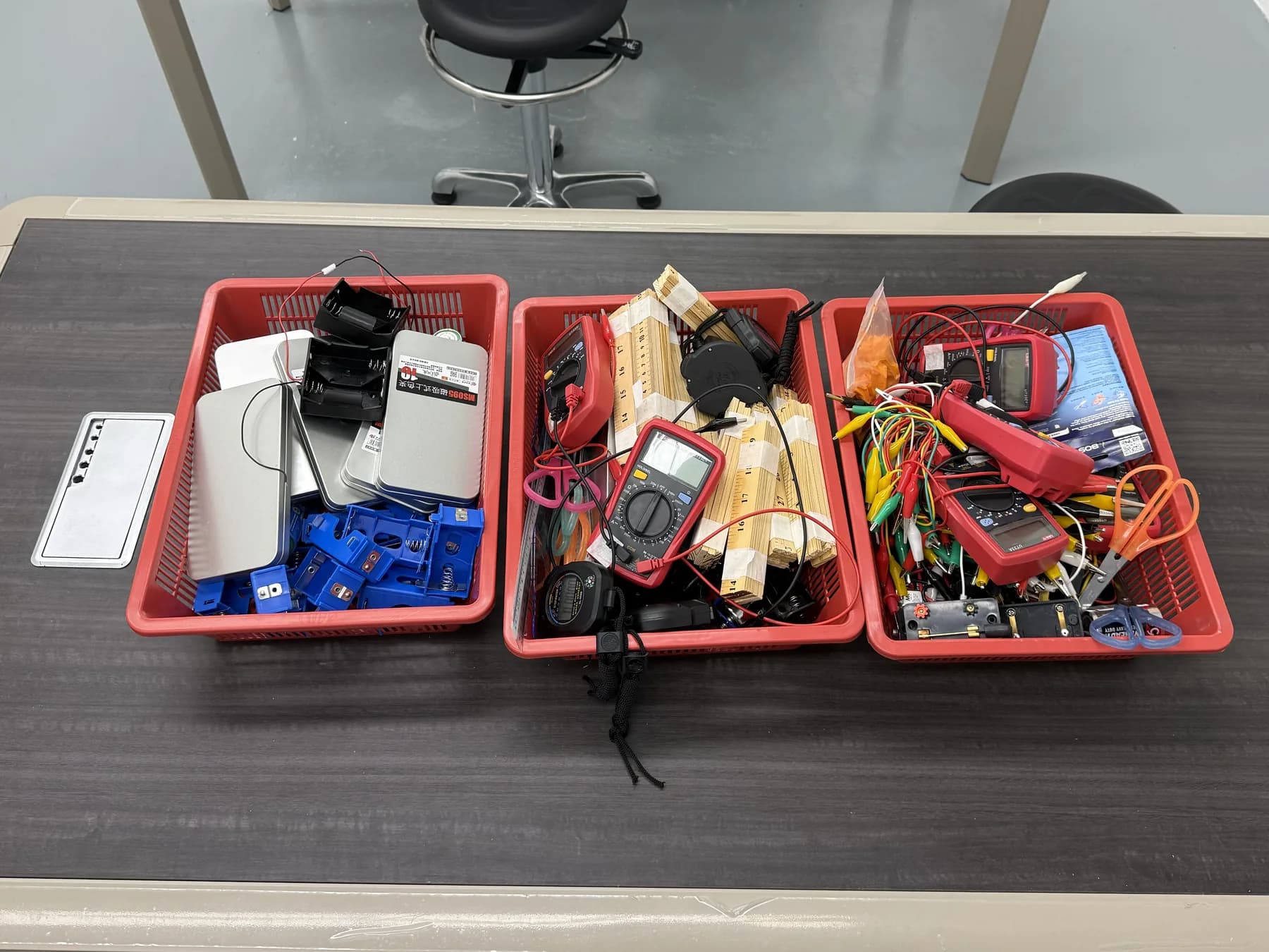 Multimeters, leads and metre rules set out for a physics practical.