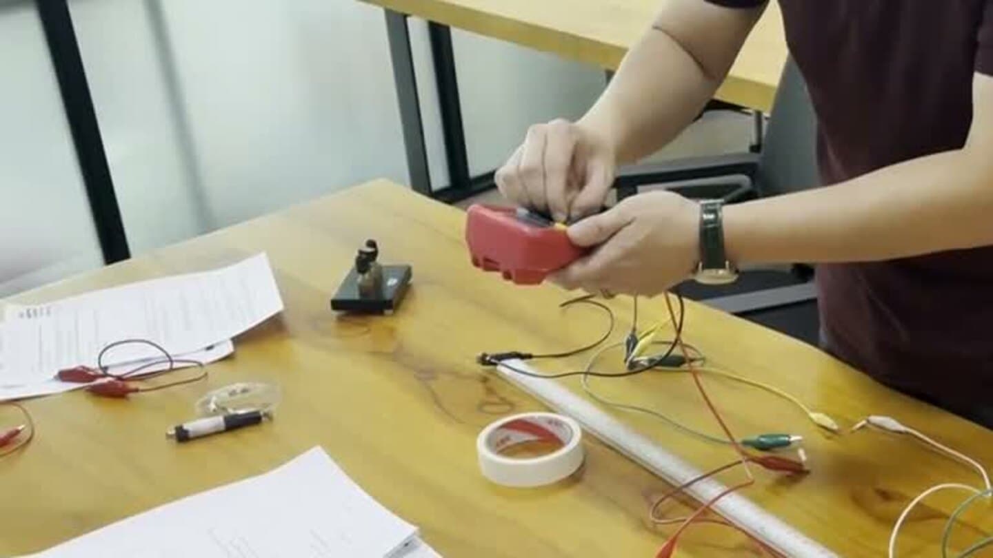 A student assembling electrical apparatus and preparing to take meter readings during an Eclat Physics practical